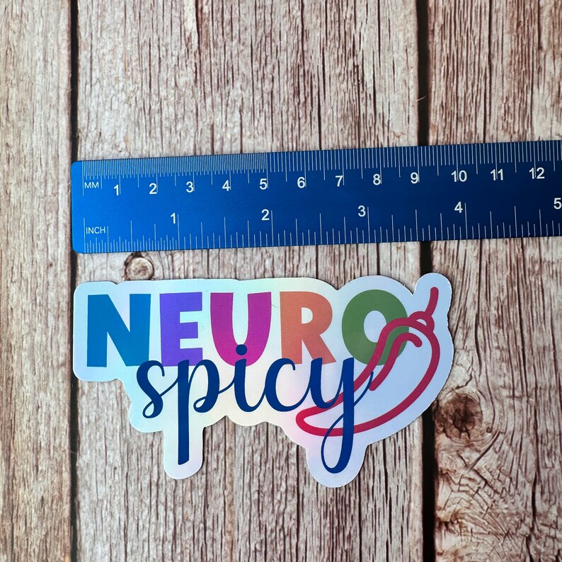 Pu&ograve; includere: Un adesivo olografico con le parole "NEURO spicy" in un font colorato, con una grafica di peperoncino. L'adesivo &egrave; lungo circa 10 cm.