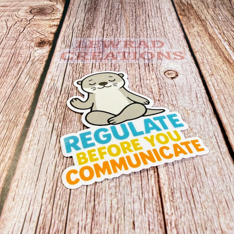 Puede incluir: Una pegatina troquelada que muestra una nutria de dibujos animados de color marr&oacute;n claro sentada en posici&oacute;n de loto con los ojos cerrados. Debajo de la nutria, el texto dice REGULATE en azul, BEFORE YOU en amarillo y COMMUNICATE en naranja.