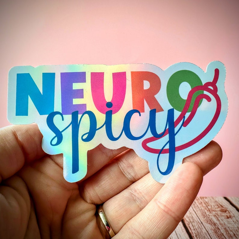 Pu&ograve; includere: Un adesivo olografico con le parole "NEURO spicy" in un mix di colori. La parola "NEURO" &egrave; in blu, viola, arancione e verde. La parola "spicy" &egrave; in corsivo blu. Una grafica di peperoncino rosso &egrave; a destra.