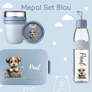 Op de afbeelding: Een Mepal Set Blau bestaande uit een lichtblauwe lunchbox, een bijpassende snackpot en een doorzichtige drinkfles met een blauwe dop. Elk item is voorzien van een afbeelding van een puppy in een mand en de naam Paul in witte letters.