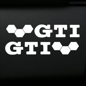 Puede incluir: Calcomanía de vinilo blanco con el texto "GTI" y un patrón de panal a cada lado.