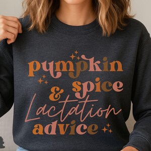 May include: Dark heather gray sweatshirt with the words "pumpkin & spice lactation advice" in orange, brown, and pink lettering. The text is stylized with star accents. The sweatshirt is a crew neck.