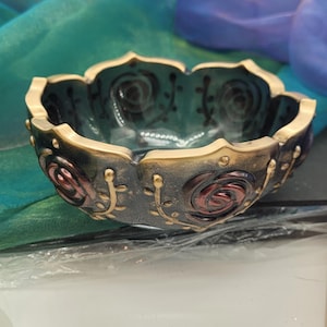 赤いバラと金色のメタリックアクセントで飾られた華やかな黒の樹脂製ボウル