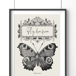 Peut inclure: Impression en noir et blanc d'un papillon avec le texte "Fly. be free" dans un cadre d&eacute;coratif. L'impression est sur un fond cr&egrave;me et porte le texte "Darby & Holt" en bas.