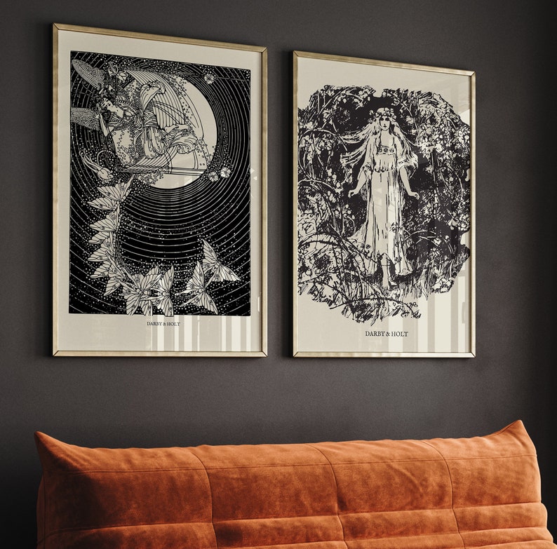 May include: Two black and white framed prints with a vintage aesthetic. The print on the left features a stylized image of a woman with wings and a crescent moon. The print on the right features a stylized image of a woman standing in a forest. Both prints have the text "Darby & Holt" at the bottom.