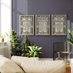 May include: Three framed prints with black and white text on a white background. The prints feature quotes from Seneca, Marcus Aurelius, and Epictetus. The frames are ornate and have a black and white design.