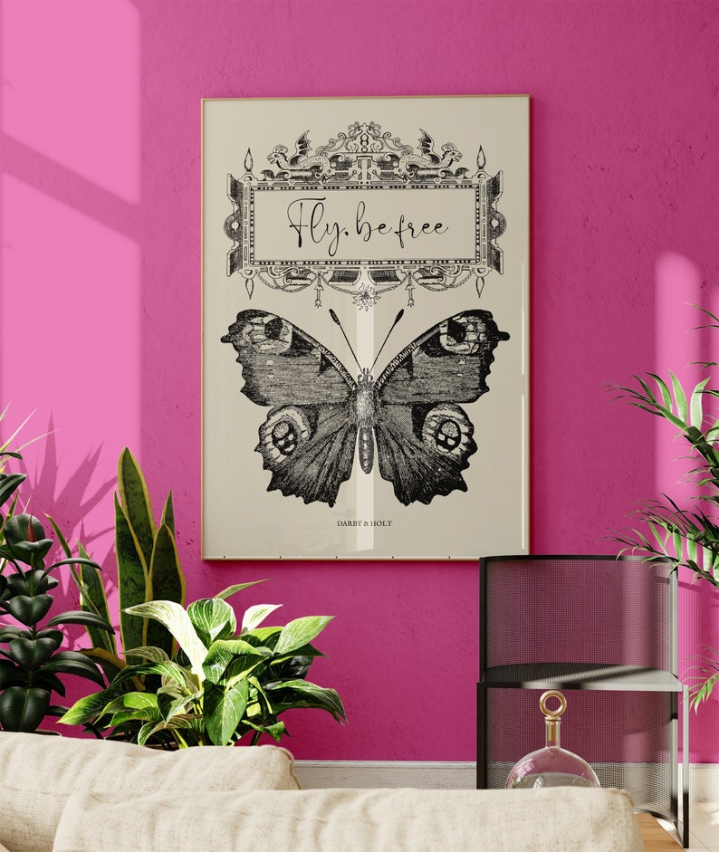 Peut inclure: Une illustration vintage en noir et blanc d'un papillon avec le texte "Fly. be free" dans un cadre d&eacute;coratif. L'impression est sur un fond cr&egrave;me et porte le texte "Darby & Holly" en bas.