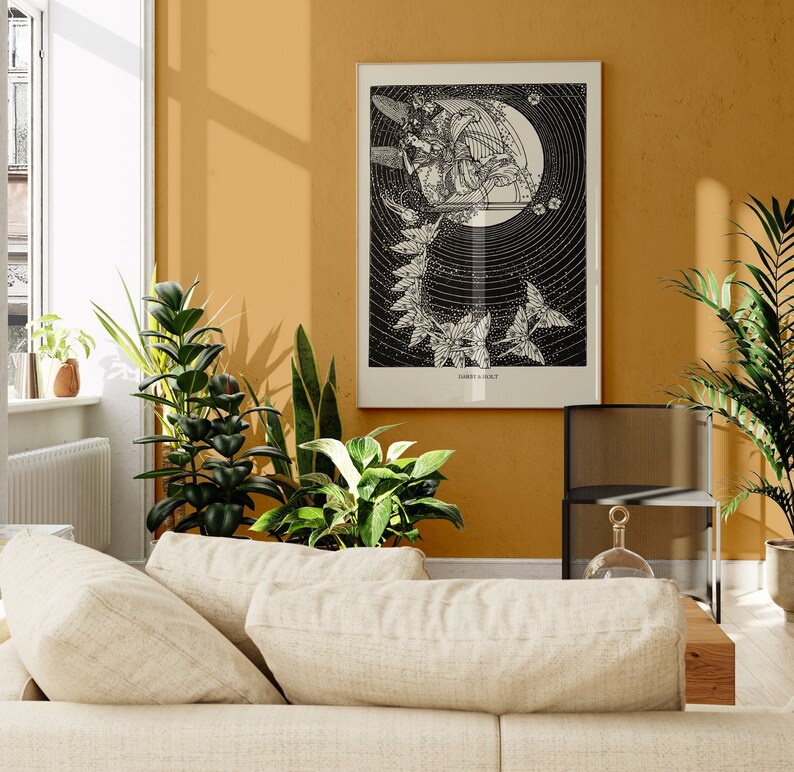 May include: A black and white illustration of a woman playing a harp with a moon and stars in the background. The illustration is framed and hanging on a yellow wall.
