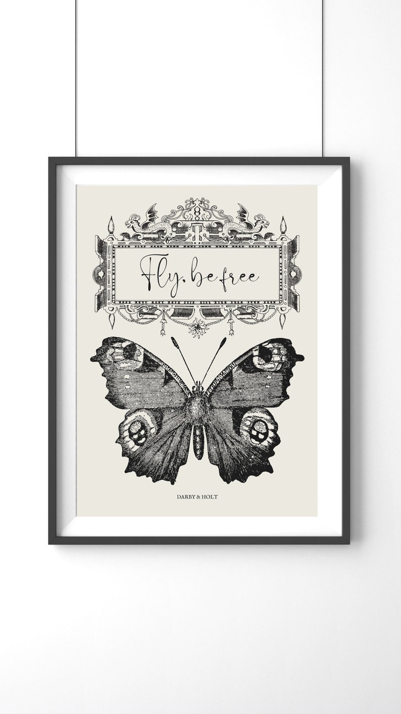 Peut inclure: Impression en noir et blanc d'un papillon avec le texte "Fly. be free" dans un cadre d&eacute;coratif. L'impression est sur un fond cr&egrave;me et porte le texte "Darby & Holt" en bas.