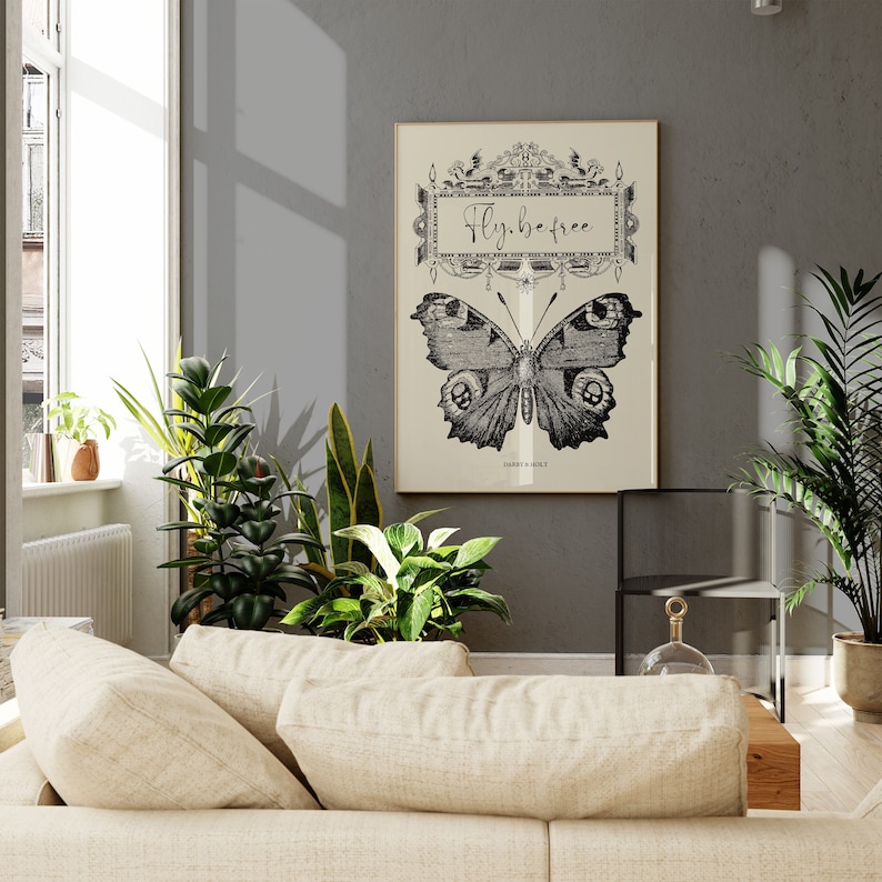 Peut inclure: Une illustration vintage en noir et blanc d'un papillon avec le texte "Fly, be free" dans un cadre d&eacute;coratif. L'illustration est sur un fond cr&egrave;me et est encadr&eacute;e dans un cadre noir.