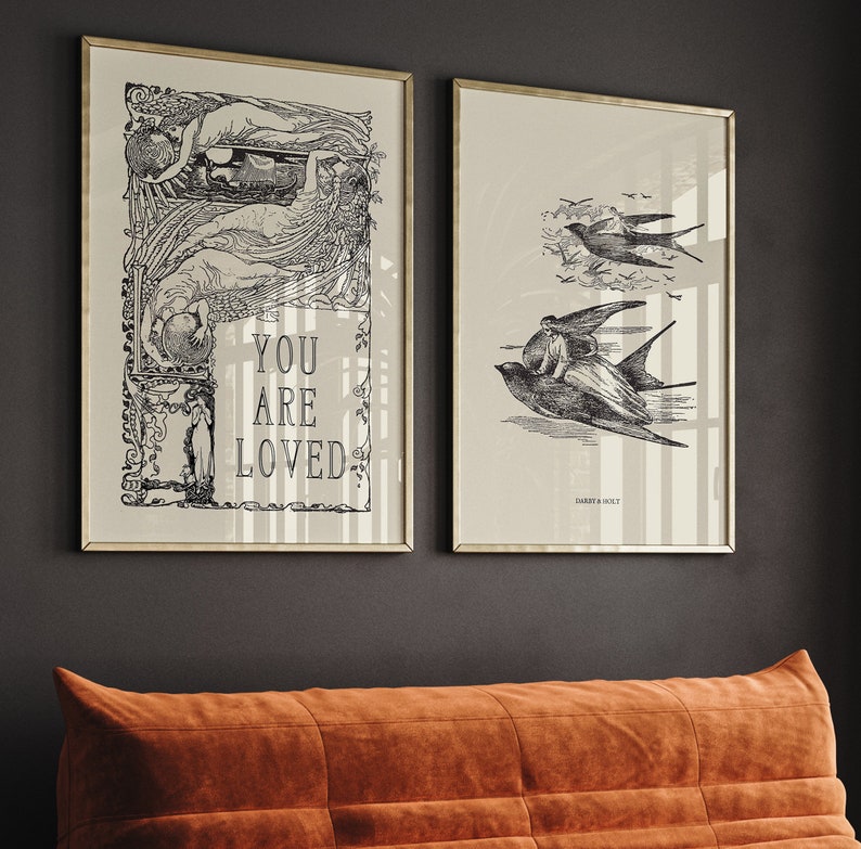May include: Two framed black and white prints with gold frames. The print on the left features a woman with wings and the text "You are loved". The print on the right features a bird with a woman riding on its back.