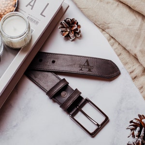 May include: A brown leather belt with a silver buckle. The belt has the name "ANTONIO" and the letter "A" engraved on it.