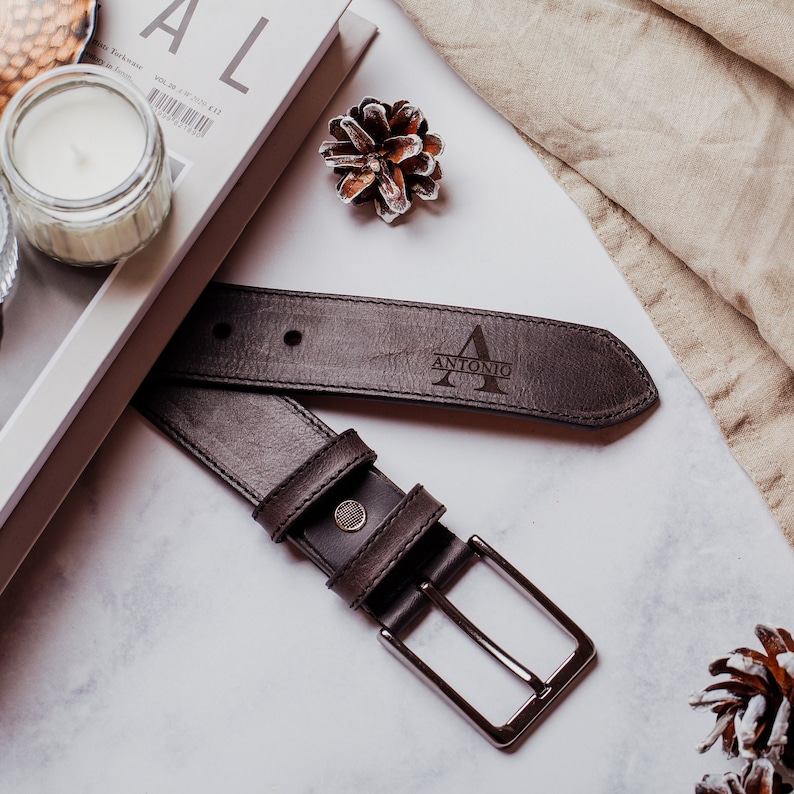 May include: A brown leather belt with a silver buckle. The belt has the name "ANTONIO" and the letter "A" engraved on it.