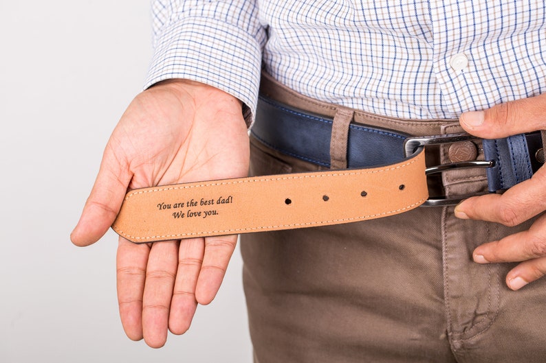May include: A brown leather belt with a blue buckle. The belt has an engraved message that reads "You are the best dad! We love you."