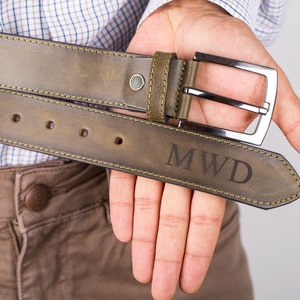 May include: A brown leather belt with a silver buckle and the initials "MWD" engraved on the strap.