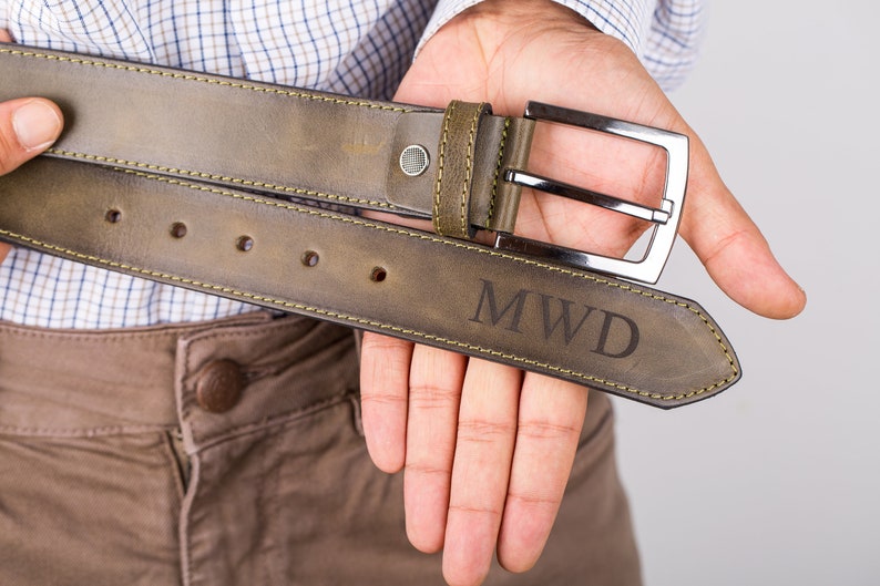 May include: A brown leather belt with a silver buckle and the initials "MWD" engraved on the strap.
