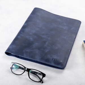 Puede incluir: Una carpeta de cuero azul oscuro con una inscripci&oacute;n personalizada que dice "TIM +"
