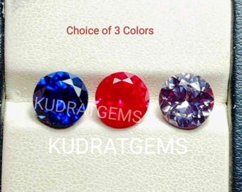 May include: Three round faceted gemstones in blue, red, and a color-changing purple-grey hue. The text "Choice of 3 Colors" and "KUDRATGEMS" is visible. These circular stones feature intricate geometric facets that reflect light across their surfaces.