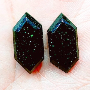 May include: A pair of dark green, faceted, geometric earrings with a glittery finish.