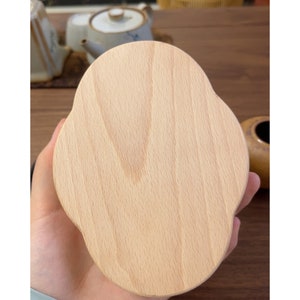 May include: A light wood coaster with a cloud-like shape. The coaster has a smooth, polished surface and is ideal for protecting surfaces from heat and spills.