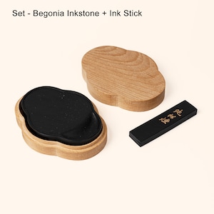 May include: A set of black inkstone and ink stick in a wooden box. The inkstone is shaped like a cloud and has a black surface with a subtle sparkle. The ink stick is black with gold lettering that reads "墨香" (Mo Xiang).