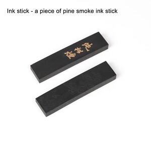May include: Two black ink sticks, one with the Chinese characters "松煙墨" in gold lettering and the other with a detailed landscape design.