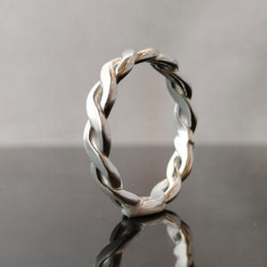 May include: A silver braided ring with a smooth, polished finish.