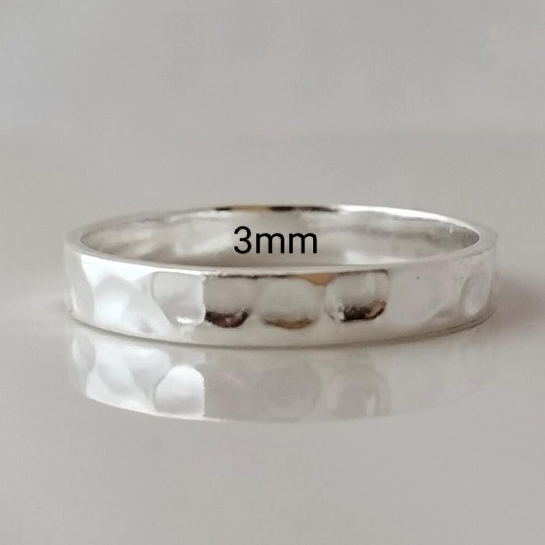 May include: A silver hammered ring with a 3mm width. The ring is smooth and shiny.