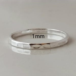 May include: A thin silver ring with a hammered texture. The ring is 1 mm wide.