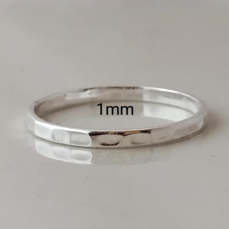 May include: A thin silver ring with a hammered texture. The ring is 1 mm wide.