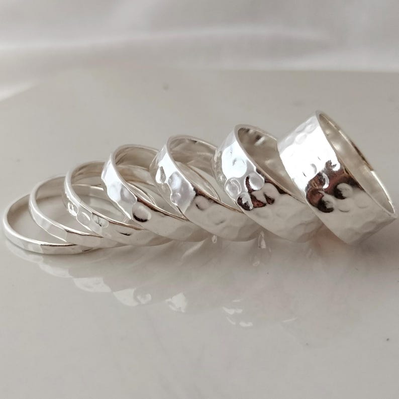 May include: A set of five silver hammered stacking rings. The rings are all different sizes and are stacked on top of each other.