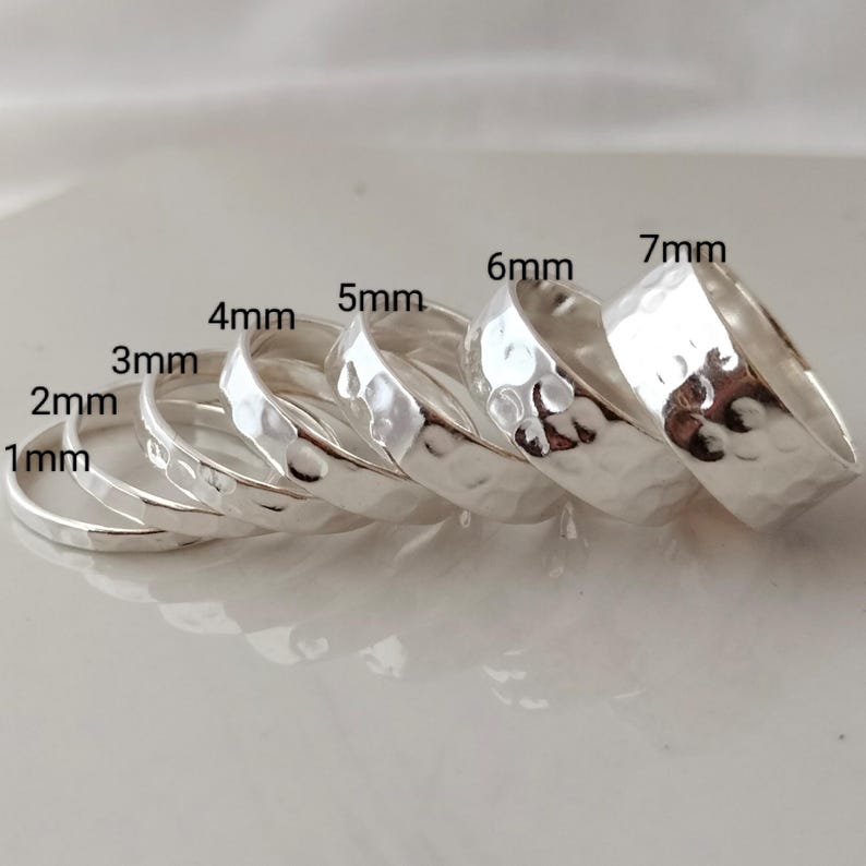 May include: A set of seven silver hammered rings, each ring is a different size, ranging from 1mm to 7mm in diameter.