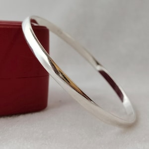 May include: A simple silver bangle bracelet with a smooth, polished finish.