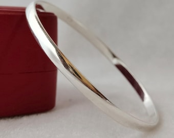 May include: A simple silver bangle bracelet with a smooth, polished finish.