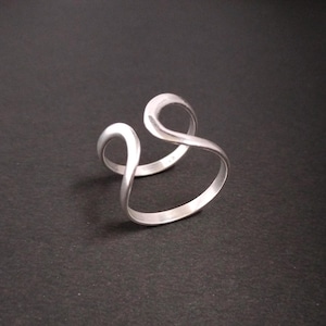 May include: A silver ring with a unique, abstract design. The ring is made of two intertwined bands that form a continuous loop.