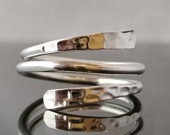 May include: A silver hammered spiral ring. The ring is made of two bands of silver that are twisted together to form a spiral shape.