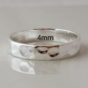 May include: A silver hammered band ring with a 4mm width.
