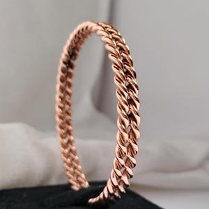 Op de afbeelding: Een roségouden gevlochten armband. De armband is gemaakt van een dikke, gedraaide draad.
