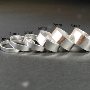 May include: A set of six silver rings in different sizes, ranging from 3mm to 8mm in diameter. The rings are stacked on top of each other, with the largest ring at the bottom and the smallest ring at the top.