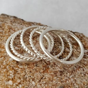 May include: Set of four silver rings, two with a twisted design and two with a smooth finish.