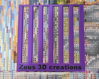 May include: Purple plastic diamond painting organizer with five rows of symbols and the text "Zeus 3D creations".