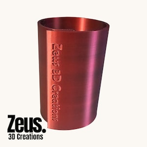 May include: A red 3D-printed cylinder with the embossed text "Zeus 3D Creations". The object has a smooth, metallic appearance and a subtle taper. The "Zeus 3D Creations" logo is also visible. The object is likely a container.