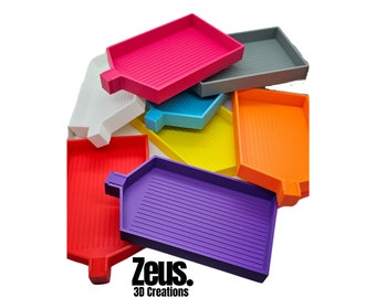 May include: Assortment of colorful plastic trays with a ridged surface. The trays are shaped like a house and are stacked on top of each other. The trays are labeled "Zeus. 3D Creations".