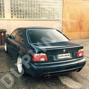 May include: A dark blue saloon car with a black rear spoiler and a number plate that reads "DUPLINOX".