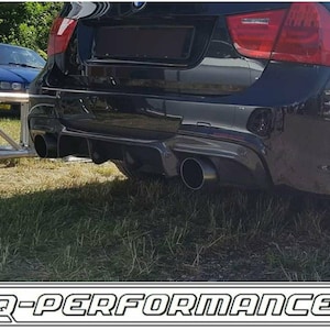 Może przedstawiać: Czarne BMW z niestandardowym zderzakiem tylnym i podwójnymi końcówkami wydechu. Samochód jest zaparkowany na trawie. Zderzak tylny ma czarny dyfuzor i czarny spojler. Końcówki wydechu są okrągłe i chromowane.