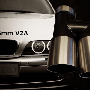 Könnte beinhalten: Ein silbernes Auto mit einem schwarzen und silbernen Doppel-Auspuffrohr. Das Auspuffrohr ist mit "2x 76mm V2A" beschriftet. Das Auto ist ein BMW E-39.