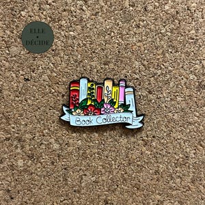 Peut inclure: Épinglette colorée en émail représentant une pile de livres avec des accents floraux et une bannière avec l'inscription "Book Collector". L'épinglette présente une variété de couleurs, notamment le rouge, le jaune, le rose et le vert, sur un fond neutre.