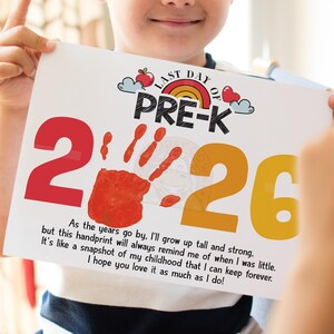 Peut inclure: Une impression souvenir de pré-maternelle blanche tenue par un enfant, avec une empreinte de main rouge, l'année 2026 et le texte "Last Day of Pre-K". L'impression comprend un arc-en-ciel, une pomme et des illustrations de cœur, ainsi qu'un message sentimental.