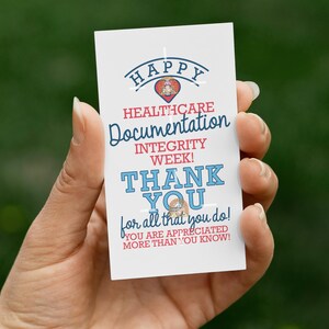 May include: A white card with text in red and blue, held in a hand. The card reads "HAPPY HEALTHCARE Documentation INTEGRITY WEEK! THANK YOU for all that you do! YOU ARE APPRECIATED MORE THAN YOU KNOW!"