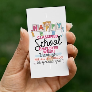 May include: A white card held in a hand with the text "HAPPY CLASSIFIED School EMPLOYEE WEEK! Thank you FOR ALL THAT YOU DO! We appreciate you!" in various colors and fonts. The card has a green background.